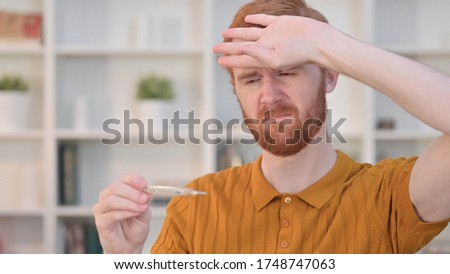 Portrait of Sick Redhead Man Checking Temperature by Thermometer 