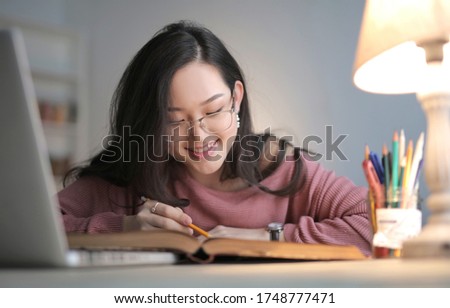 A selective focus shot of a pretty female with pink top reading a book
