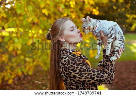 Beautiful young blond hair woman carring a cat . She is walking in a park. 