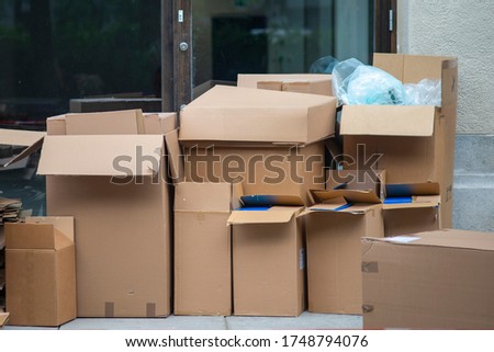 Many cardboard boxes outside of a house. Photo symbolizes moving in, moving out, packing and transportation of goods.  Royalty-Free Stock Photo #1748794076