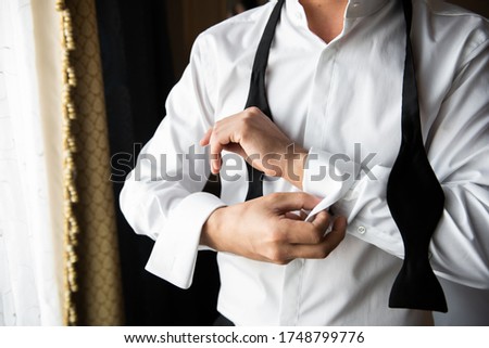 Dressing a man. Fastens buttons. Standing by the window.