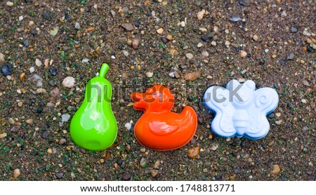 children's toys in the sandbox on the squeak. green pear, red duck, blue butterfly