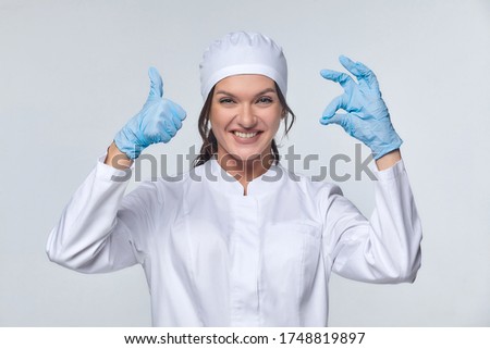 Medical concept.  a young woman in a white coat with a stethoscope, a doctor, a trainee. A female hospital worker writes in a notebook, looks at the camera and smiles, Studio, White background