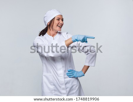 Medical concept.  a young woman in a white coat with a stethoscope, a doctor, a trainee. A female hospital worker writes in a notebook, looks at the camera and smiles, Studio, White background