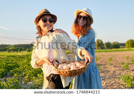 Agriculture, farming organic eco products. Women mother and daughter with basket of eggs, lifestyle, nature, garden, sunset, country side background