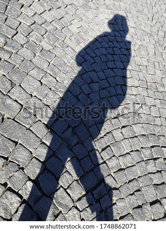 Textural stone pavement background with shadow walking citizen on sunny day