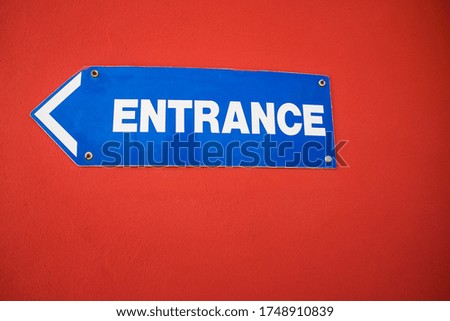 Entrance Sign mounted on a bright red wall