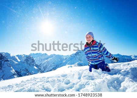 Cute beautiful laughing smiling girl about to throw snow in the air close portrait over blue sky and mountains on sunny day