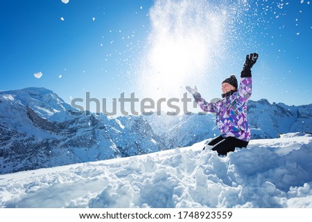Happy teen beautiful ski girl portrait throw snow in the air sitting over mountain top range view