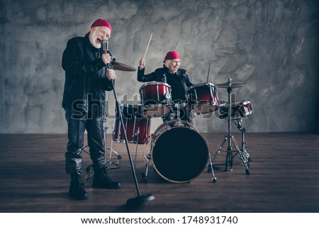 Photo of retired lady man rock popular band group perform concert play drum instruments sing song mic wear trendy rocker leather outfit bandana isolated grey concrete wall background