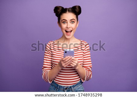 Photo of funny lady two cute buns hold telephone check followers blog open mouth good news wear white red casual striped shirt isolated purple pastel color background