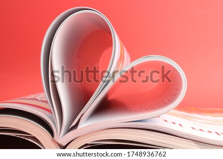 open magazine formed as a heart showing love to read red background