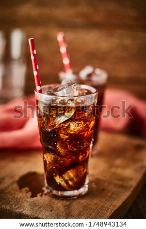 Close up glass of refreshing cola with ice on table.
