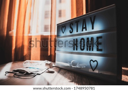 Coronavirus home sign lightbox with text STAYHOME glowing in light. COVID-19 banner to promote self isolation staying at home. Apartment background