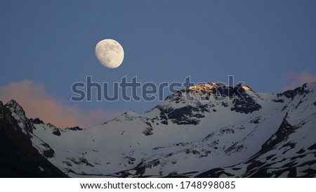 half moon, clouds and blue sky with view to the alps
