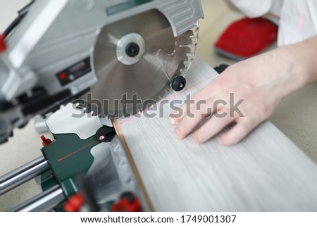 Man uses circular saw table while cutting laminate. Laminate laying technology with Click lock. Features of sawing laminate. Flooring option. Imitation shades and textures various types wood