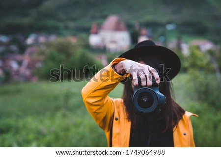 Portrait of woman a photographer covering her face with the dslr photo camera. Copy space, travel and wanderlust concept
