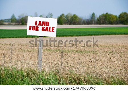 A sign is in front of the land. Land for sale.