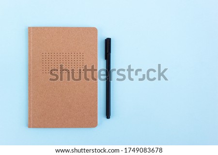 Creative bullet journal and black pen on blue background. Planning and goal setting concept. Place for text, top view.