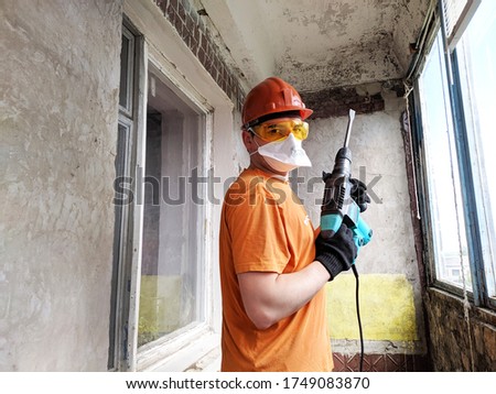 A man with a hammer drill in his hands. Worker with hammer breaking interior wall plastering