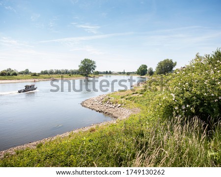 boat on river ijssel between deventer and zutphen on sunny summer day Royalty-Free Stock Photo #1749130262