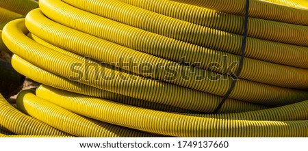 Large roll of yellow flexible pipe at a building site