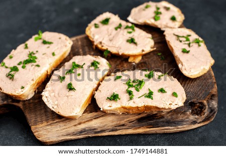 Chicken pate on toast with fresh parsley on a cutting board on a stone background	