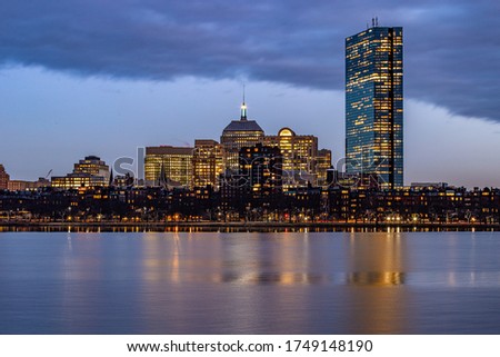 Blue hour cityscape buildings reflecting in water.