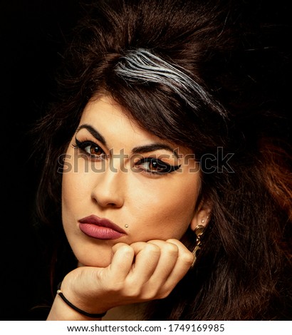 Beautiful young woman in Amy Winehouse style. She has a high fluffy hairstyle and expressive eye makeup. Royalty-Free Stock Photo #1749169985