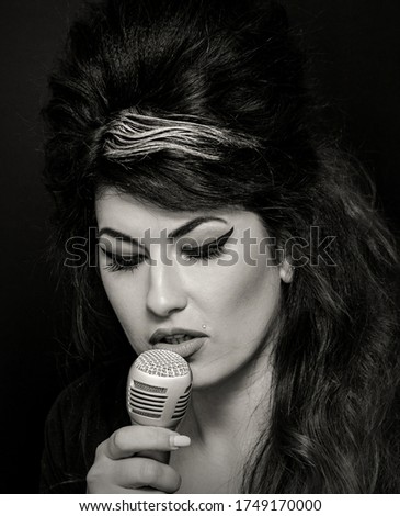 Beautiful young woman in Amy Winehouse style. She has a high fluffy hairstyle and expressive eye makeup. Royalty-Free Stock Photo #1749170000