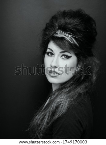 Beautiful young woman in Amy Winehouse style. She has a high fluffy hairstyle and expressive eye makeup. Royalty-Free Stock Photo #1749170003