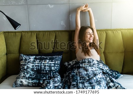 Glowing woman stretching while getting up in the morning