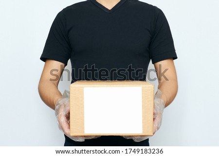 A delivery man holding a cardboard box with copy space on a white background. The concept of online ordering, business purchasing, and courier delivery to your home
