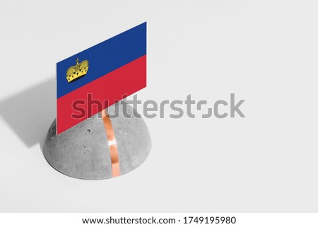 Liechtenstein flag tagged on rounded stone. White isolated background. Side view minimal national concept.