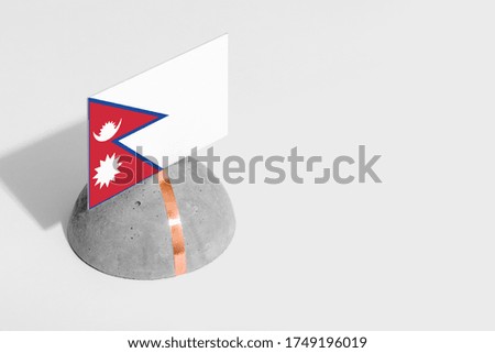 Nepal flag tagged on rounded stone. White isolated background. Side view minimal national concept.