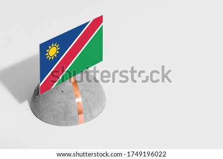 Namibia flag tagged on rounded stone. White isolated background. Side view minimal national concept.