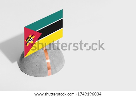 Mozambique flag tagged on rounded stone. White isolated background. Side view minimal national concept.