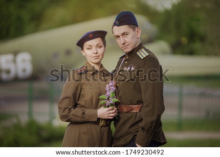 Young adult man and woman in the uniform of pilots of the Soviet Army of the period of World War II. Military uniform with shoulder straps of a major and a cap on his head. Photo in retro style.