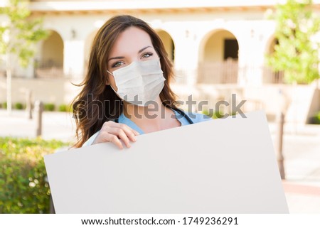 Female Doctor or Nurse Wearing Protective Face Mask Holding Blank Sign.