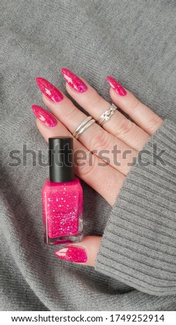 Female hand with long nails and pink fuchsia bottle manicure with nail polish