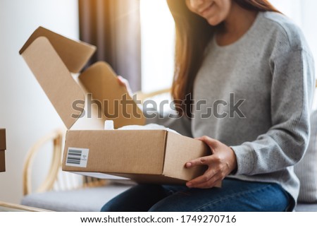 A beautiful young asian woman receiving and opening a postal parcel box at home for delivery and online shopping concept Royalty-Free Stock Photo #1749270716