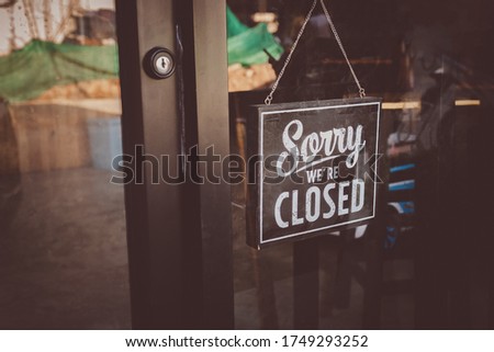 Label 'Sorry we're closed' notice sign wood board hanging on door front coffee shop.
