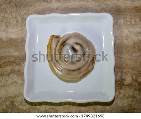 View from above of a cinnamon roll with icing on top.