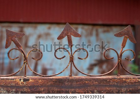 Rusty wrought iron fence with pointy arrow shapes.