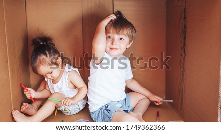 Beautiful little children draw with felt-tip pens and play in box, activity for children at home.