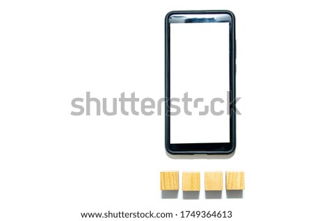 Wooden cubes and smartphone on a white background. The smartphone lies to the right under it four wooden cubes together and with a distance. There is a place for text