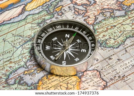 Round compass and ancient map (close up). Royalty-Free Stock Photo #174937376
