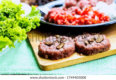 Beef or pork meat and Insect for hamburger prepared on old wooden table
