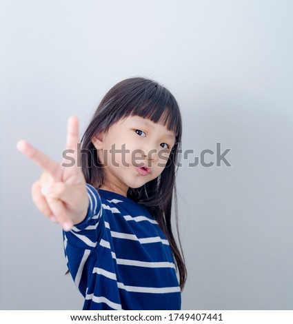 beautiful child girl standing over isolated white background smiling looking to the camera showing fingers doing victory sign. Number two.