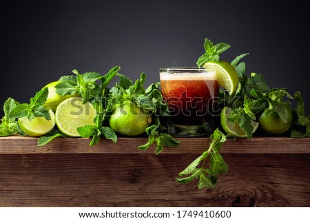 Carbonated drink or cocktail with limes and mint on a old wooden table. Black background.